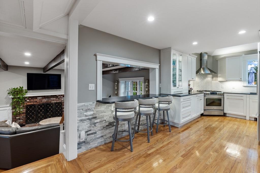 25 Curtis Street Marblehead, MA 01945 - Photo 7 of 28 a kitchen with stainless steel appliances granite countertop a stove top oven a sink dishwasher a dining table and chairs with wooden floor