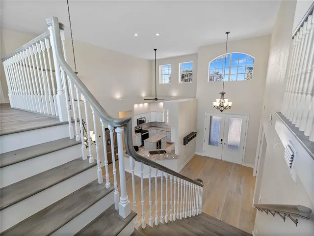 a view of an empty room with window and chandelier fan