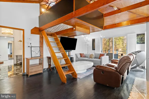a living room with furniture a flat screen tv and floor to ceiling window