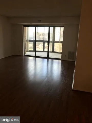 an empty room with wooden floor and windows with curtains