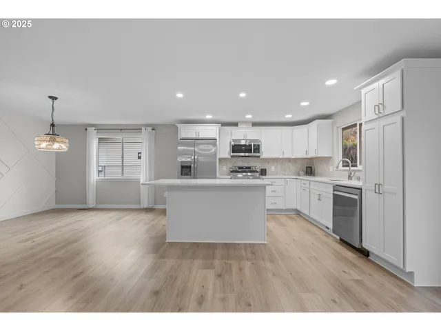 a large kitchen with cabinets wooden floor and stainless steel appliances
