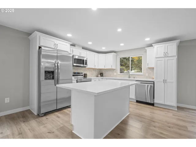 a kitchen with kitchen island a sink stainless steel appliances and white cabinets