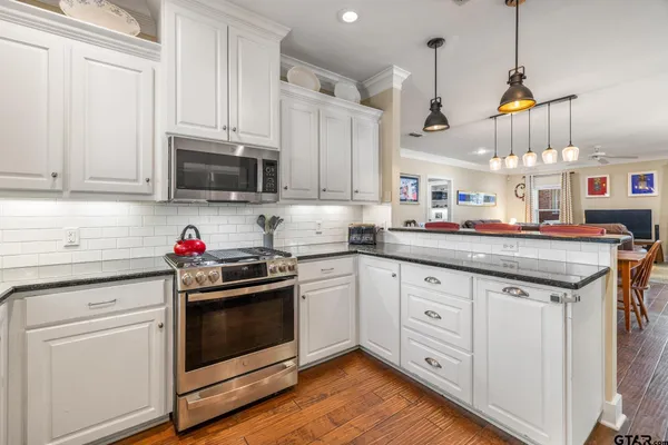 a kitchen with granite countertop a sink stainless steel appliances and cabinets