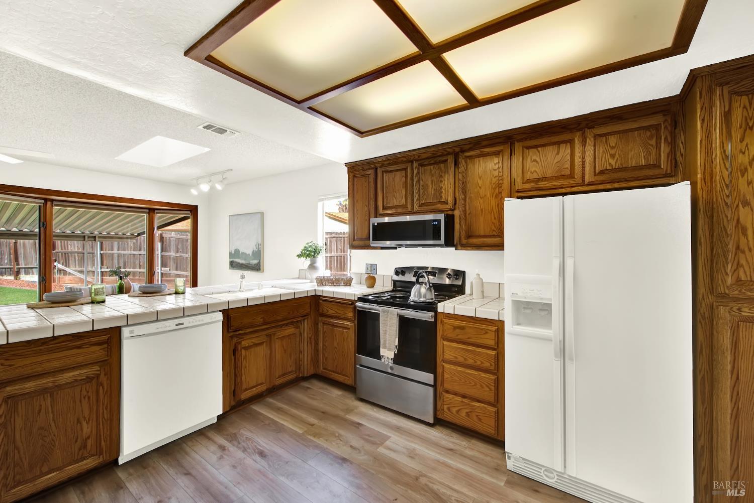 2219 Channing Court Fairfield, CA 94533 - Photo 22 of 81 a kitchen with stainless steel appliances granite countertop white cabinets a sink a stove a refrigerator with grey cabinets and wooden floor