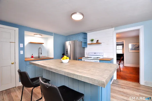 a kitchen with refrigerator and wooden floor