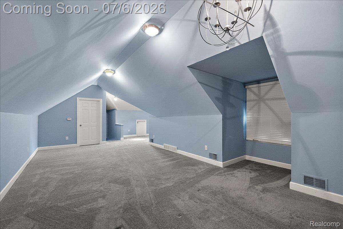 1051 Devonshire Road Grosse Pointe, MI 48230 - Photo 61 of 98 Spacious upper-level room featuring light blue walls, sloped ceilings, and gray carpet flooring