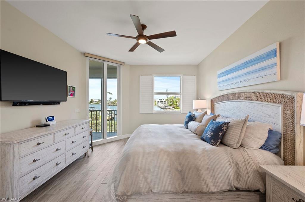 450 Launch Circle, Unit 201 Naples, FL 34108 - Photo 14 of 43 a bedroom with a bed and a flat screen tv on the dresser
