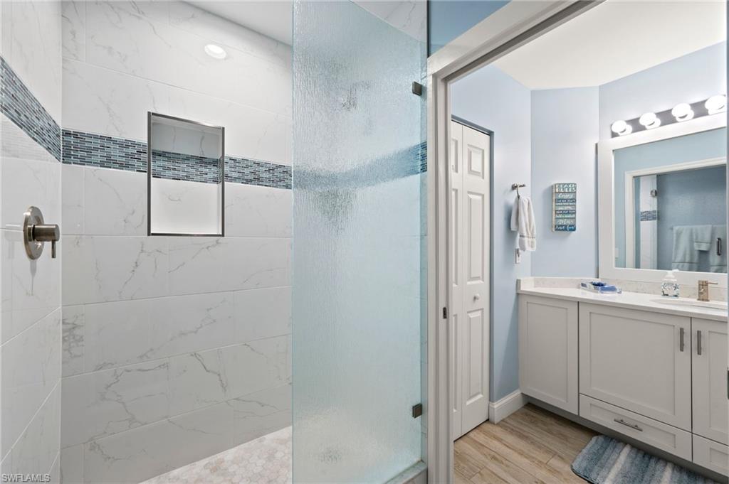450 Launch Circle, Unit 201 Naples, FL 34108 - Photo 22 of 43 a bathroom with a double vanity sink a mirror and a shower