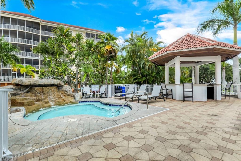 450 Launch Circle, Unit 201 Naples, FL 34108 - Photo 32 of 43 a view of a patio with a table and chairs under an umbrella