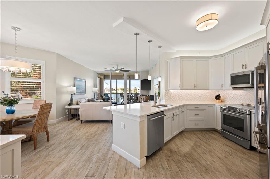 450 Launch Circle, Unit 201 Naples, FL 34108 - Photo 5 of 43 a open kitchen with sink cabinets and wooden floor