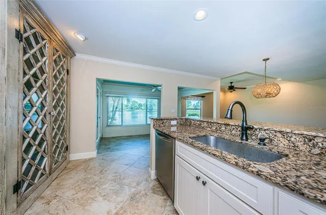 an empty room with wooden floor chandelier fan and windows