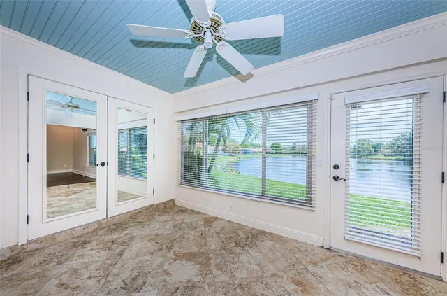 an empty room with wooden floor fan and windows
