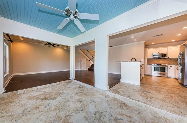 an empty room with wooden floor fan and windows