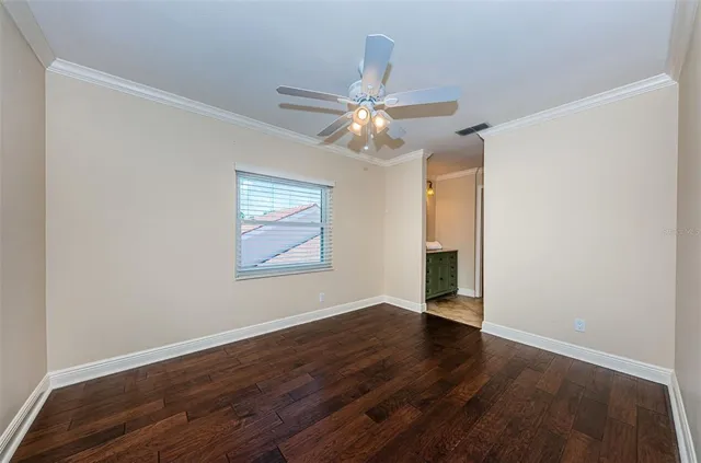 an empty room with wooden floor and fan