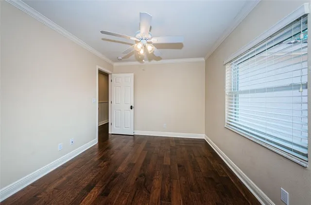 an empty room with wooden floor fan and windows