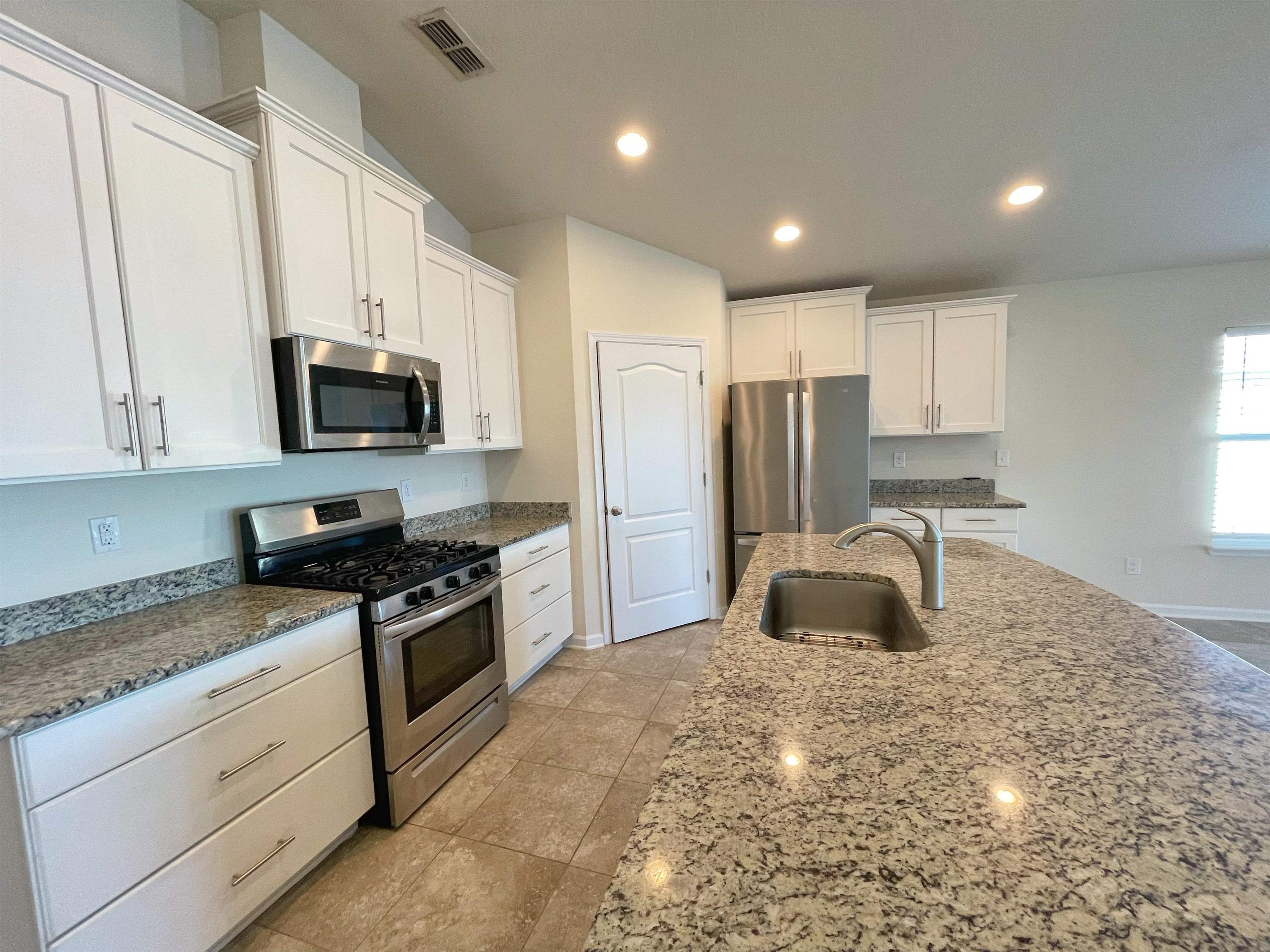 578 Deer Crossing Road St. Augustine, FL 32086 - Photo 6 of 28 a kitchen with kitchen island granite countertop a stove sink microwave and refrigerator