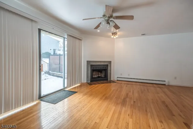 a view of an empty room with glass door and wooden floor