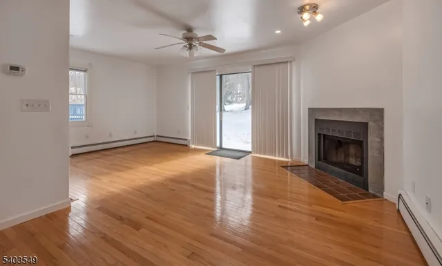 an empty room with wooden floor fireplace and windows