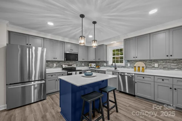 a kitchen with refrigerator a sink dishwasher a stove a dining table and chairs