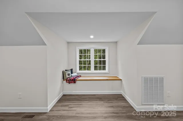 a view of an empty room with a window and wooden floor