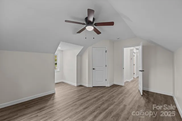 an empty room with wooden floor cabinet and windows