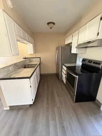 an empty room with wooden floor closet and windows
