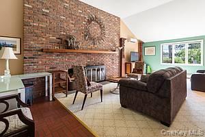 178 Barnes Road, Unit MAIN HOUSE Brookhaven, NY 11955 - Photo 3 of 5 Living area with a brick fireplace, vaulted ceiling, and brick patterned floors