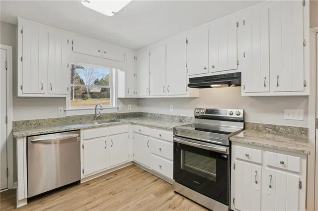 a kitchen with granite countertop white cabinets and white appliances