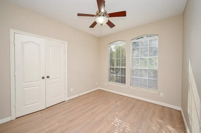 a view of an empty room with a window and wooden floor
