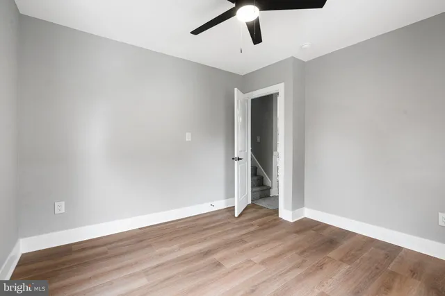 an empty room with wooden floor and ceiling fan