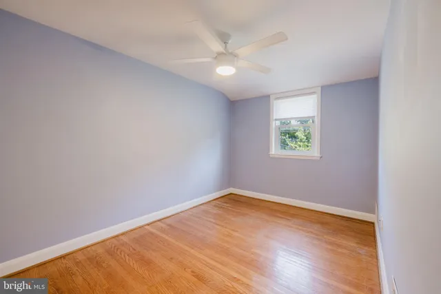 an empty room with wooden floor ceiling fan and windows
