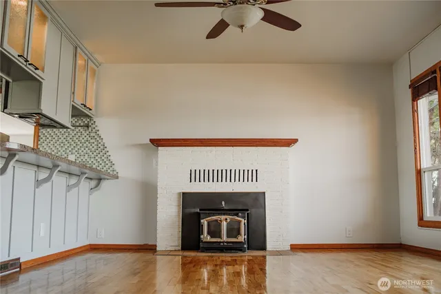 a view of an empty room with wooden floor fireplace and a window