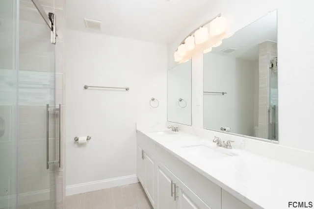 a bathroom with a double vanity sink mirror and shower