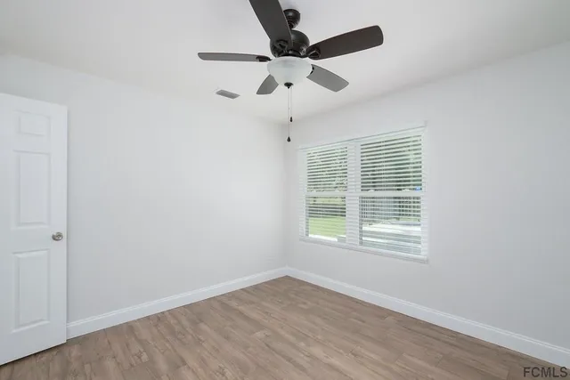 an empty room with a window and a ceiling fan