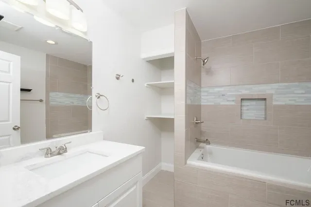 a bathroom with a tub sink shower and two mirror