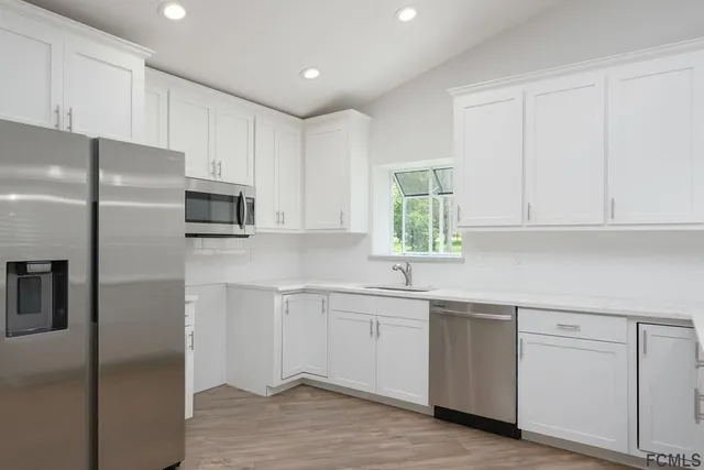 a kitchen with white cabinets white stainless steel appliances and sink