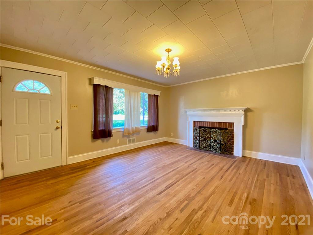 8930 Cool Springs Road Woodleaf, NC 27054 - Photo 2 of 42 a view of an empty room with wooden floor fireplace and a window