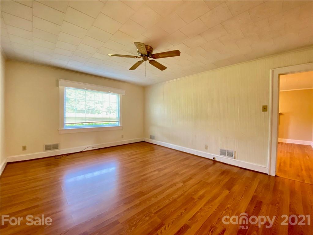 8930 Cool Springs Road Woodleaf, NC 27054 - Photo 6 of 42 an empty room with wooden floor chandelier fan and windows