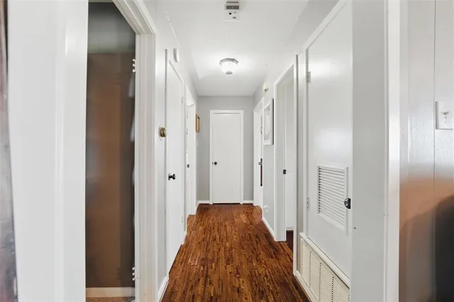 a view of a hallway with wooden floor and a bathroom