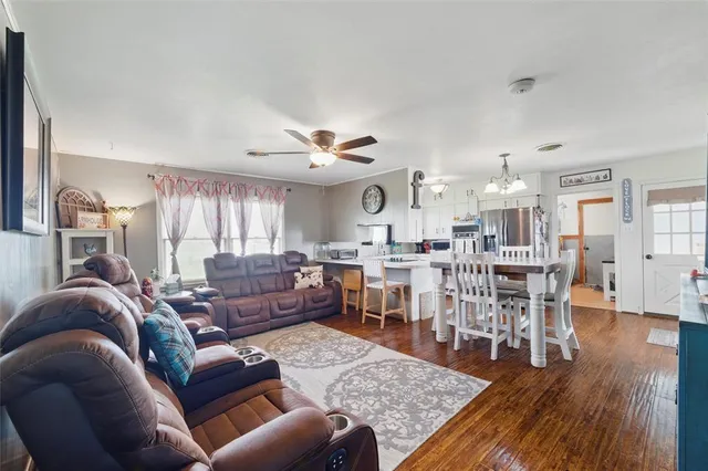 a living room with furniture kitchen view and a wooden floor
