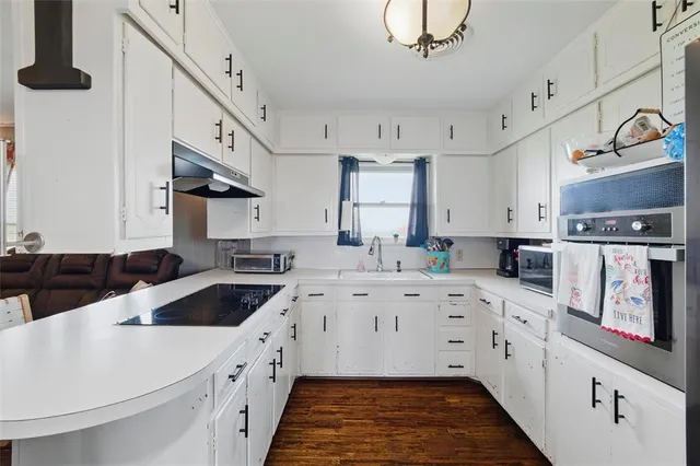 a kitchen with white cabinets sink and stove