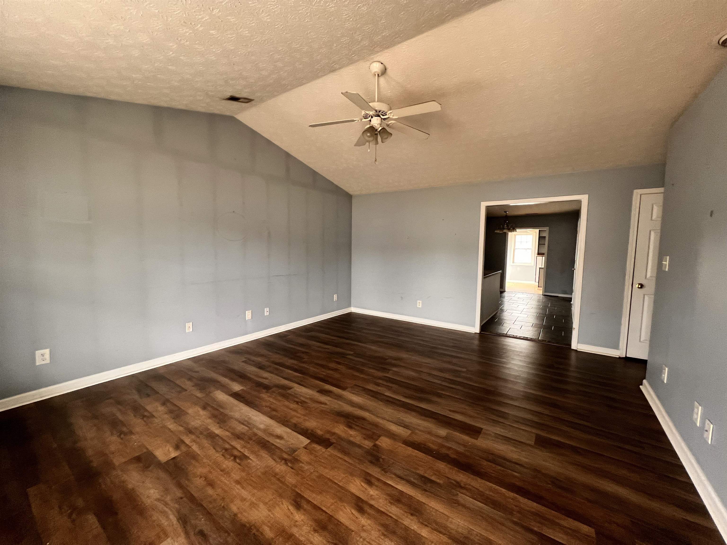 4027 Douglas Fir Lane Murrells Inlet, SC 29576 - Photo 2 of 22 Empty room with a textured ceiling, vaulted ceiling, ceiling fan, and dark wood-style flooring