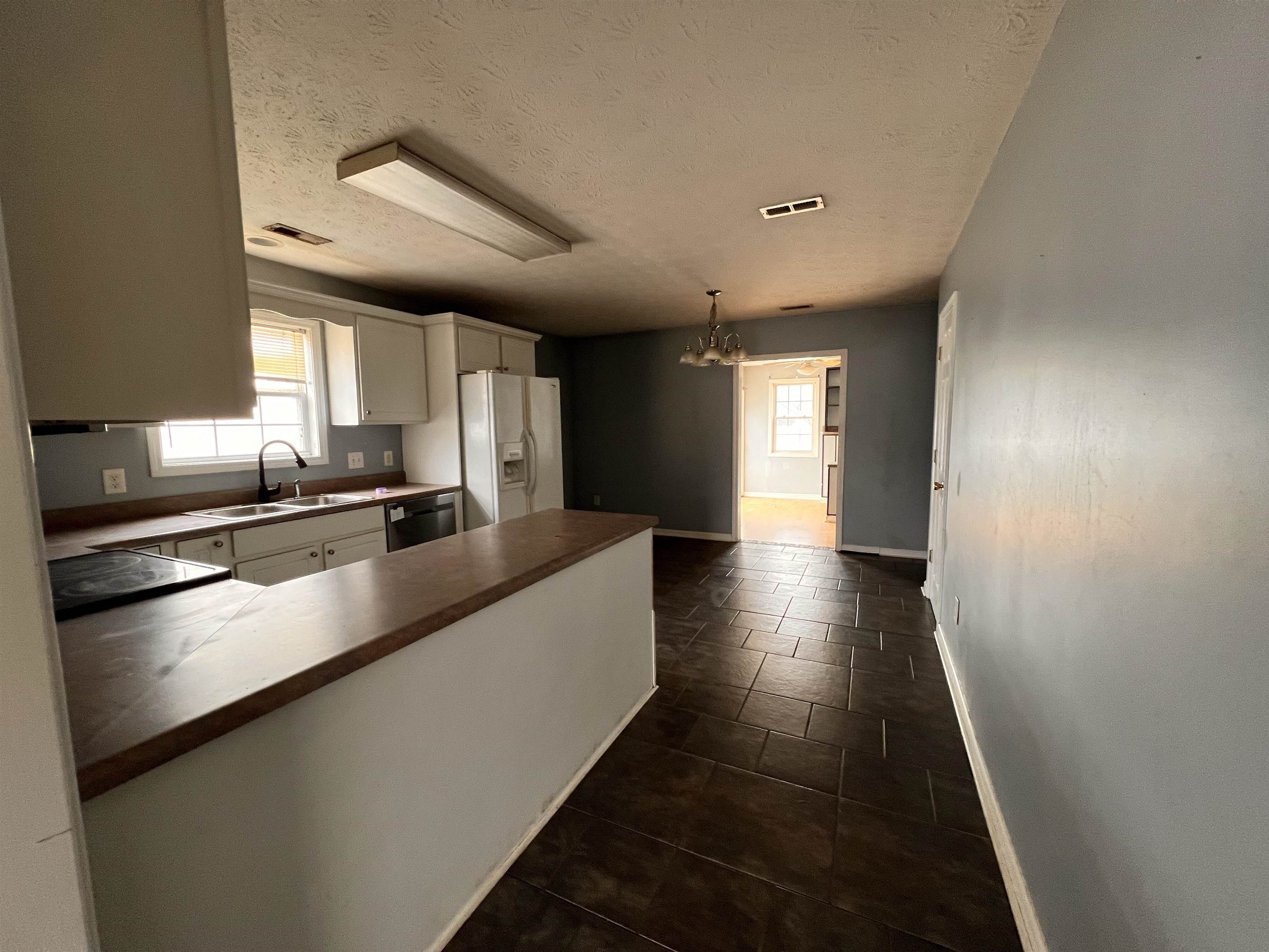 4027 Douglas Fir Lane Murrells Inlet, SC 29576 - Photo 4 of 22 Kitchen featuring a chandelier, white cabinetry, white fridge with ice dispenser, pendant lighting, and a textured ceiling