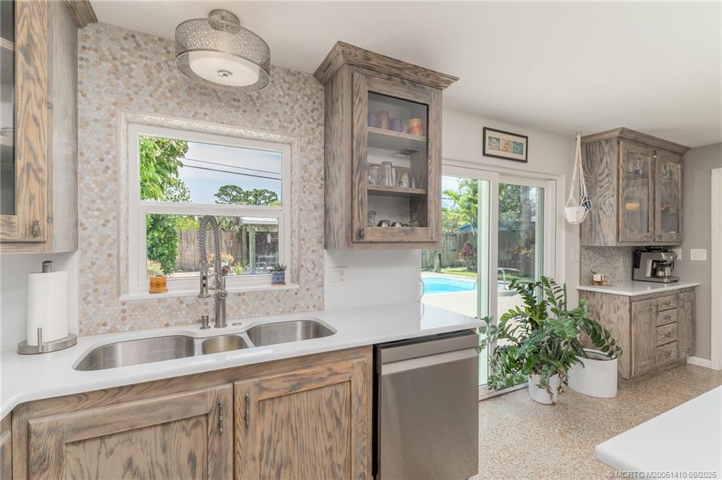 2859 Northeast Hickory Ridge Avenue Jensen Beach, FL 34957 - Photo 15 of 32 a kitchen with stainless steel appliances a sink a large window and cabinets