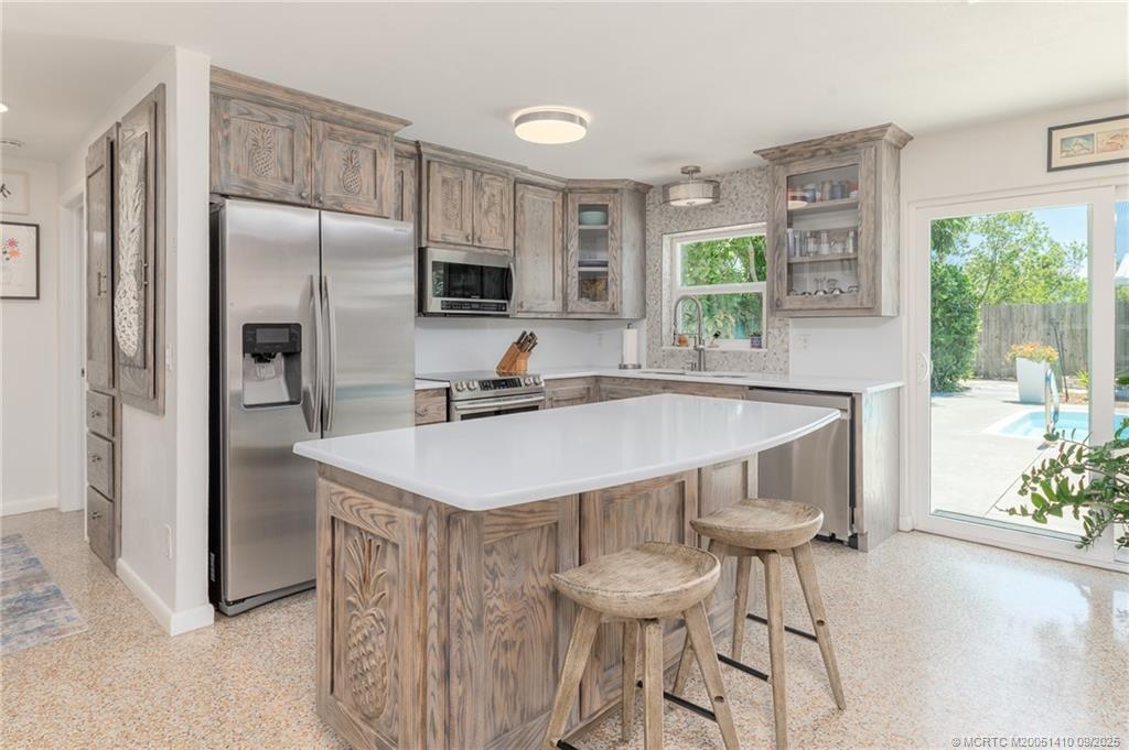 2859 Northeast Hickory Ridge Avenue Jensen Beach, FL 34957 - Photo 16 of 32 a kitchen with a table chairs refrigerator and microwave
