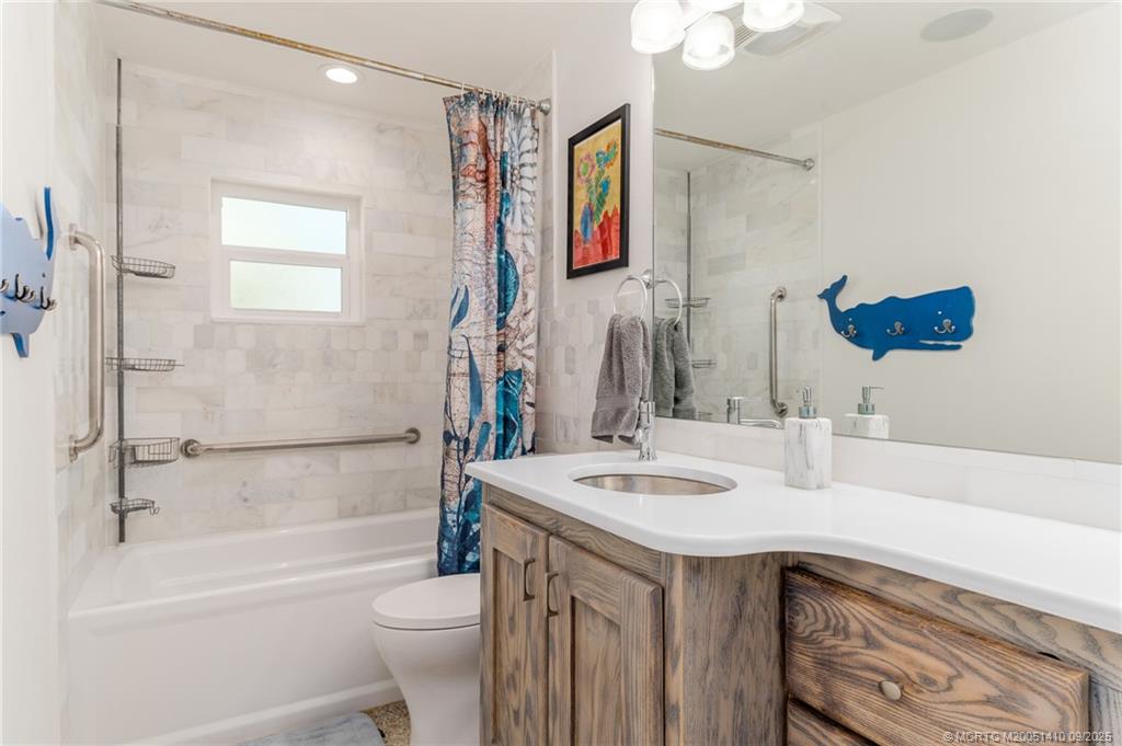 2859 Northeast Hickory Ridge Avenue Jensen Beach, FL 34957 - Photo 6 of 32 a bathroom with a sink a toilet and shower