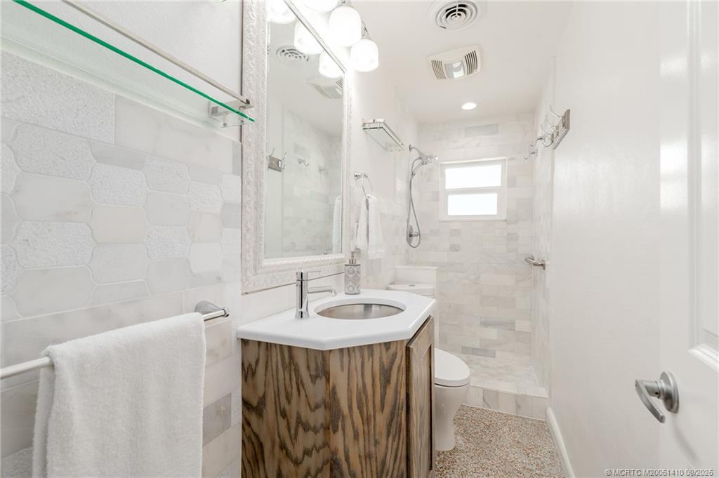 2859 Northeast Hickory Ridge Avenue Jensen Beach, FL 34957 - Photo 7 of 32 a bathroom with a sink a mirror and a shower