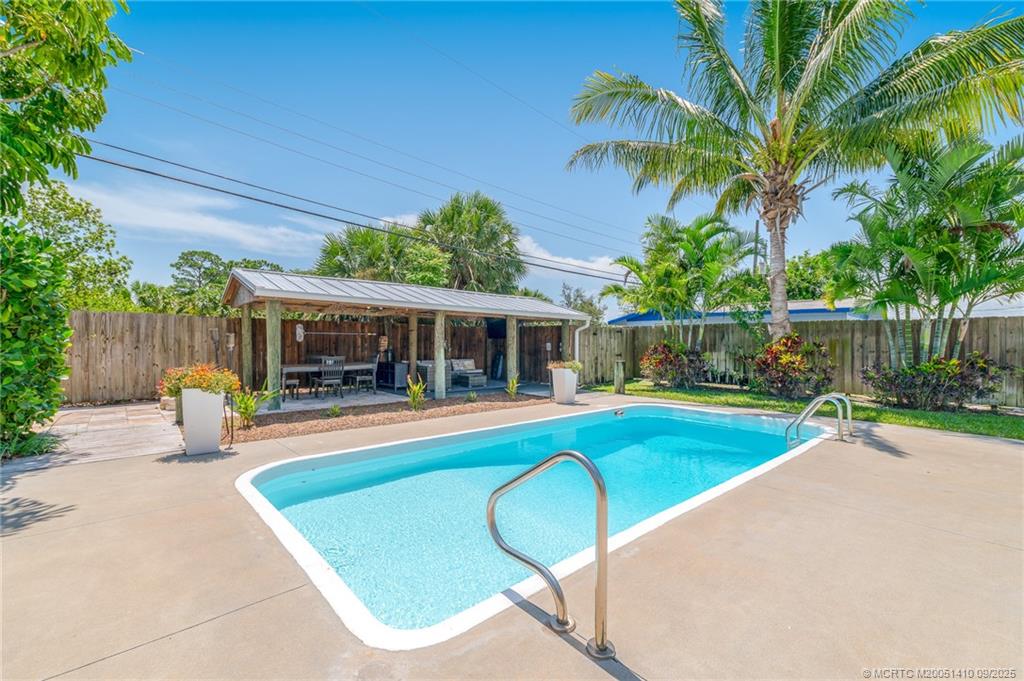 2859 Northeast Hickory Ridge Avenue Jensen Beach, FL 34957 - Photo 9 of 32 a view of a house with a swimming pool and a patio