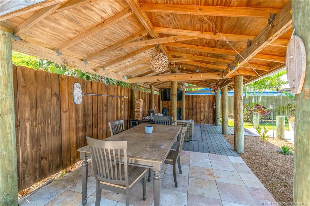 2859 Northeast Hickory Ridge Avenue Jensen Beach, FL 34957 - Photo 10 of 32 a view of a patio with table and chairs with wooden floor and fence