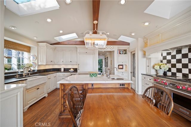 a large kitchen with stainless steel appliances a stove a sink dishwasher and white cabinets with wooden floor